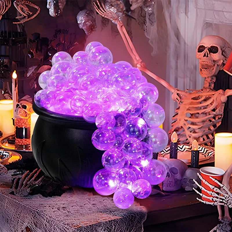 Black Halloween witch cauldron with glowing bubbling ball decoration on a table